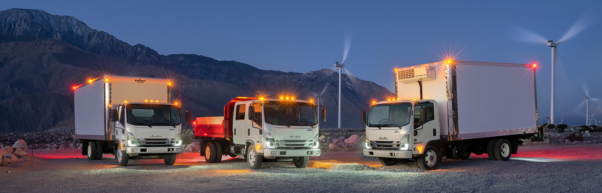 Fleet of Isuzu trucks at dusk.